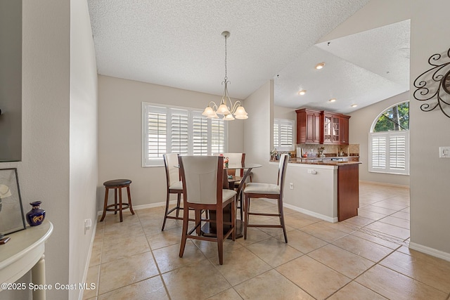 4983 Erin Ln, Melbourne, FL 32940 - dining area featuring baseboards, a chandelier, lofted ceiling, light tile patterned floors, and a textured ceiling