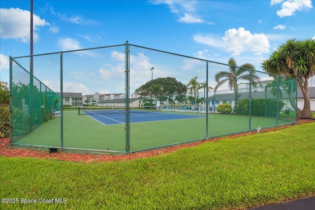 view of tennis court with fence and a lawn