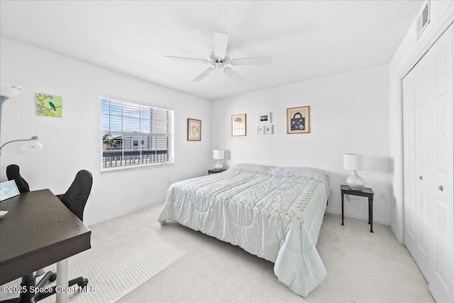 bedroom featuring ceiling fan, light colored carpet, visible vents, baseboards, and a closet