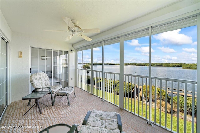 sunroom with a ceiling fan and a water view