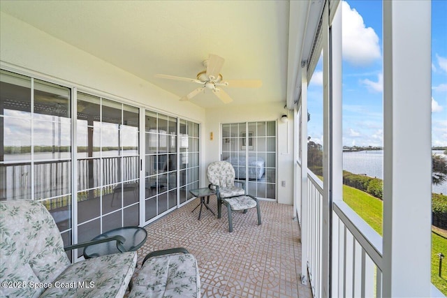 sunroom / solarium with ceiling fan and a water view