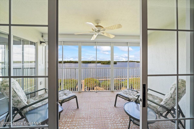 sunroom with a ceiling fan and a water view