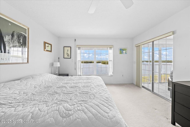 carpeted bedroom featuring access to outside, ceiling fan, and a textured ceiling