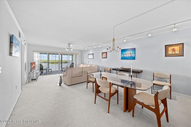 dining room featuring light carpet, baseboards, a textured ceiling, and ceiling fan with notable chandelier