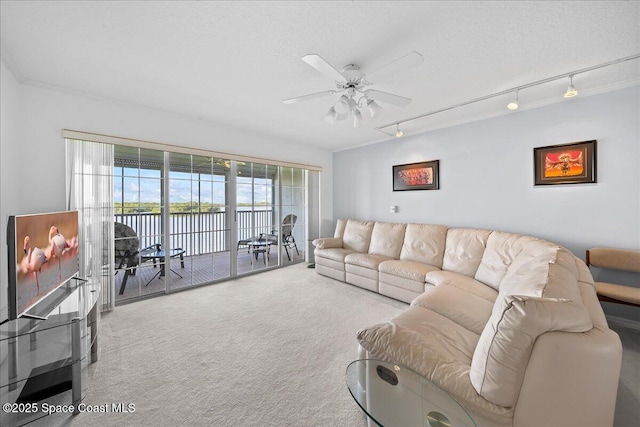 carpeted living room with a water view, a textured ceiling, track lighting, and a ceiling fan