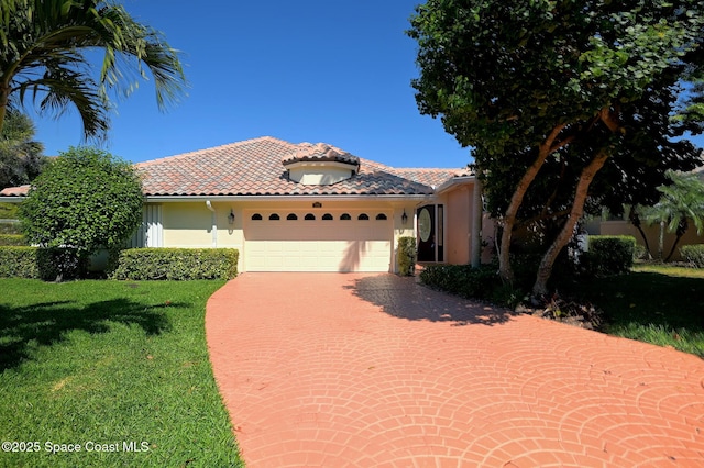 mediterranean / spanish home featuring a garage, stucco siding, a tiled roof, decorative driveway, and a front yard