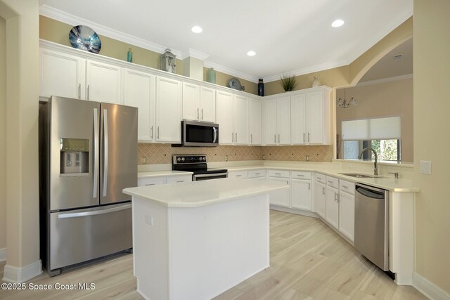 kitchen with stainless steel appliances, backsplash, a kitchen island, and a sink