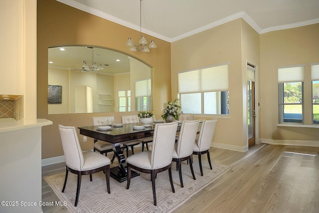 dining room with baseboards, a healthy amount of sunlight, an inviting chandelier, crown molding, and light wood-type flooring