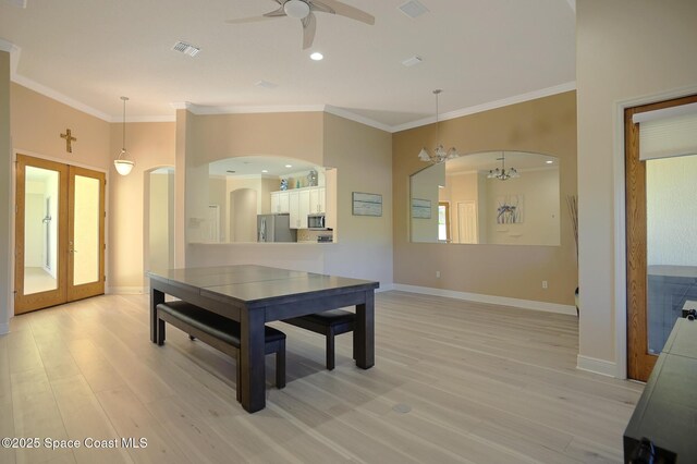 dining room with arched walkways, ornamental molding, and light wood-style flooring