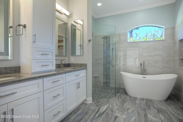 full bath with double vanity, a soaking tub, crown molding, a shower stall, and a sink