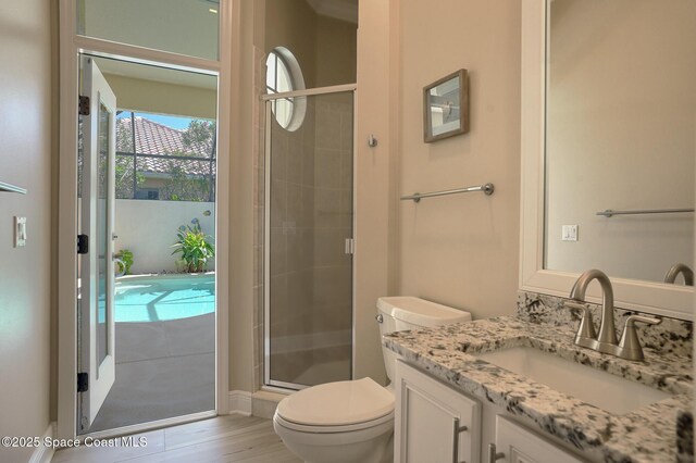 full bathroom with toilet, a stall shower, wood finished floors, and vanity