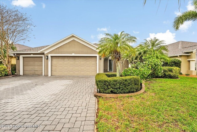 view of front of property with a garage, a front lawn, decorative driveway, and stucco siding