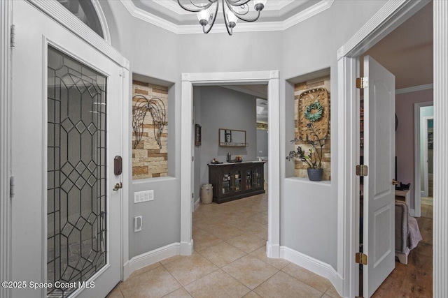 foyer featuring light tile patterned floors, ornamental molding, a chandelier, and baseboards