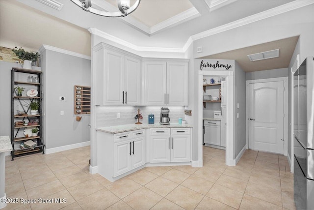 kitchen featuring ornamental molding, tasteful backsplash, light stone counters, and light tile patterned floors