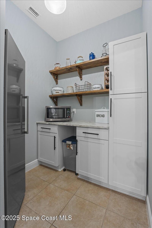 kitchen featuring stainless steel appliances, light tile patterned floors, visible vents, and white cabinetry