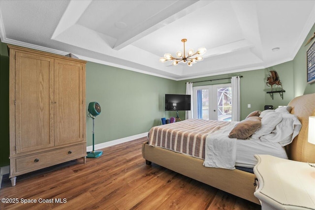 bedroom with access to exterior, a raised ceiling, wood finished floors, and an inviting chandelier