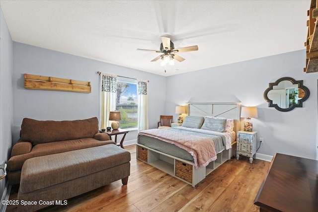 bedroom with a ceiling fan, baseboards, and wood finished floors