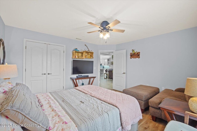 bedroom with ceiling fan, light wood finished floors, and a closet