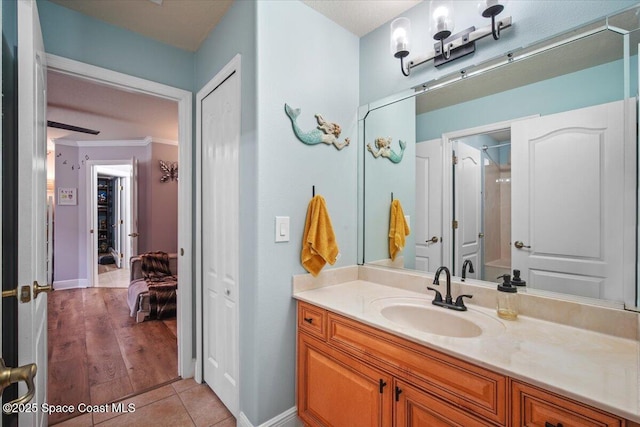 bathroom with tile patterned flooring, baseboards, crown molding, and vanity