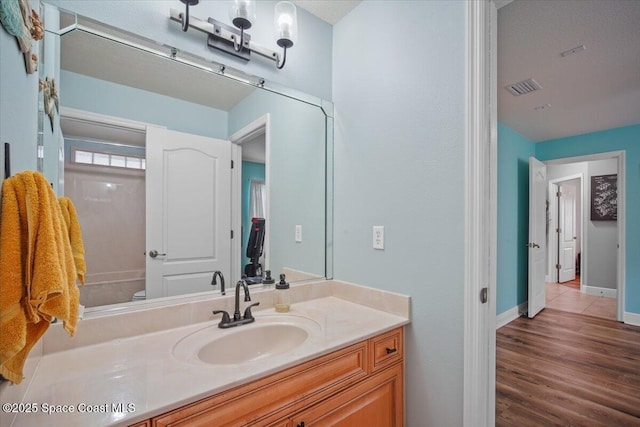 bathroom with baseboards, visible vents, toilet, wood finished floors, and vanity