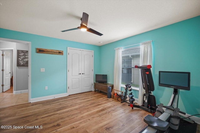 exercise area featuring ceiling fan, wood finished floors, and baseboards