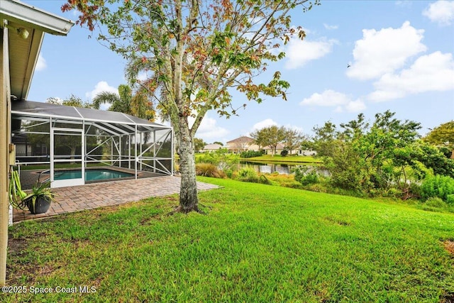 view of yard featuring a water view, glass enclosure, an outdoor pool, and a patio