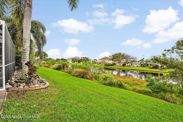 view of yard featuring glass enclosure and a water view