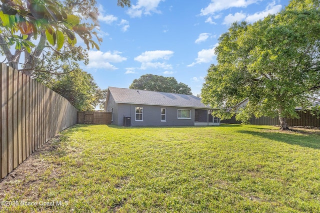 back of house featuring a fenced backyard, a lawn, central AC, and stucco siding