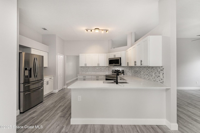 kitchen with visible vents, stainless steel appliances, a peninsula, light countertops, and decorative backsplash