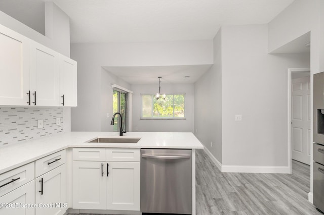 kitchen with white cabinetry, a peninsula, a sink, dishwasher, and tasteful backsplash