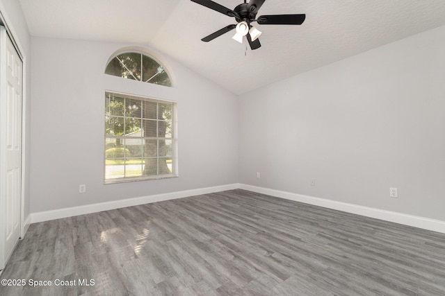 spare room with baseboards, wood finished floors, a ceiling fan, and vaulted ceiling