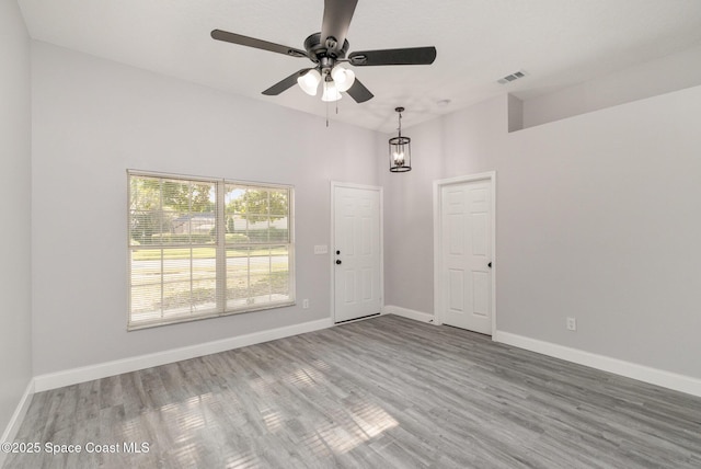 empty room with a ceiling fan, wood finished floors, baseboards, and visible vents