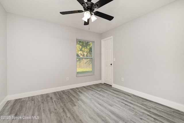 spare room with wood finished floors, baseboards, and ceiling fan