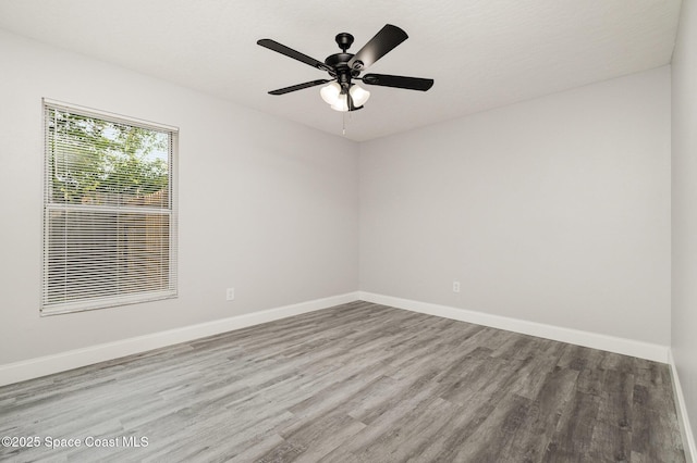 empty room featuring ceiling fan, baseboards, and wood finished floors