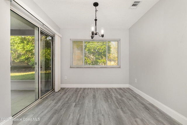 unfurnished dining area featuring a wealth of natural light, visible vents, baseboards, and wood finished floors