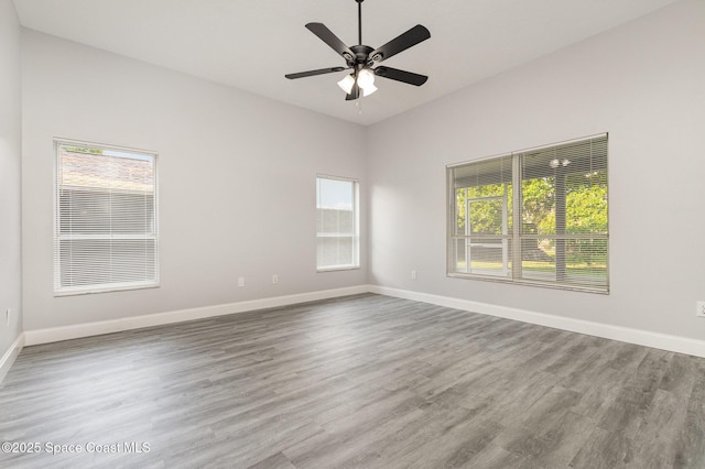 empty room featuring ceiling fan, baseboards, a healthy amount of sunlight, and wood finished floors