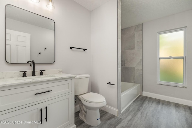 bathroom featuring toilet, a textured ceiling, wood finished floors, baseboards, and vanity