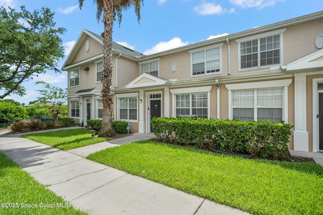 view of property featuring a front lawn and stucco siding