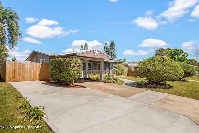 view of front facade with concrete driveway, a front lawn, and fence