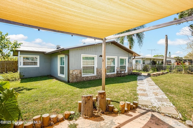 exterior space with stone siding, fence, and a front yard