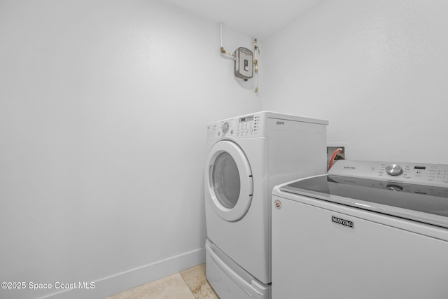 laundry area featuring laundry area, baseboards, washing machine and clothes dryer, and light tile patterned floors