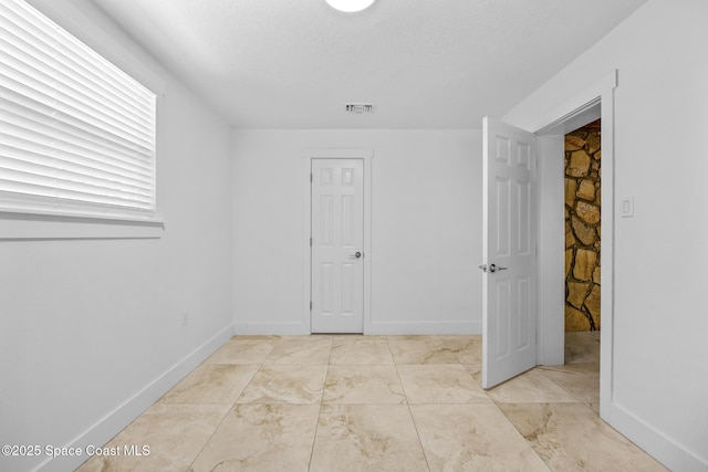 spare room featuring baseboards, visible vents, and a textured ceiling