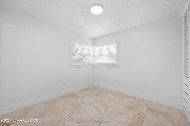 spare room featuring a textured ceiling and baseboards