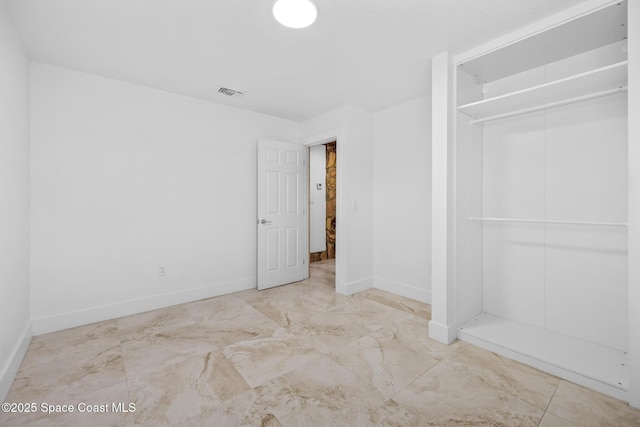 unfurnished bedroom with marble finish floor, baseboards, visible vents, and a closet