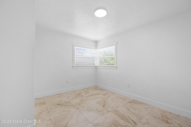 unfurnished room with a textured ceiling and baseboards