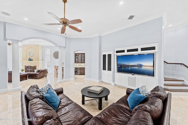 living area with visible vents, crown molding, baseboards, decorative columns, and arched walkways