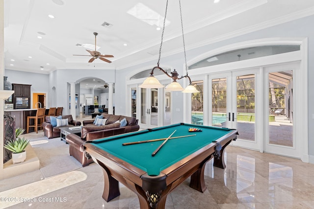 rec room featuring visible vents, a tray ceiling, decorative columns, french doors, and arched walkways