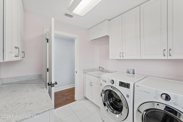 laundry area with visible vents, separate washer and dryer, light tile patterned flooring, cabinet space, and a sink