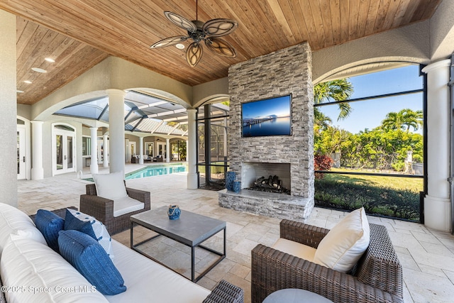 view of patio featuring a ceiling fan, an outdoor living space with a fireplace, french doors, an outdoor pool, and a lanai