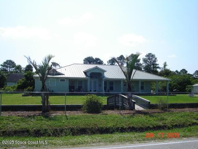 view of front of property with fence private yard, a standing seam roof, metal roof, and a front yard